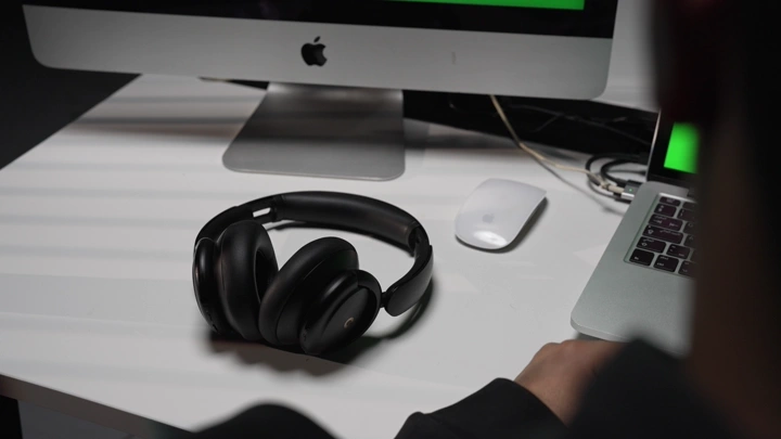 رجل يلبس سماعة رأس في مكتب بجانب حاسوب، لقطة داخلية.