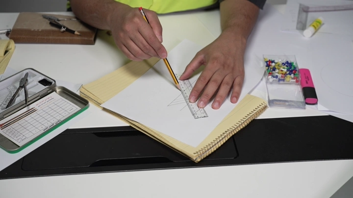 رجل يرسم بمسطرة وقلم على مكتب، لقطة مقربة.