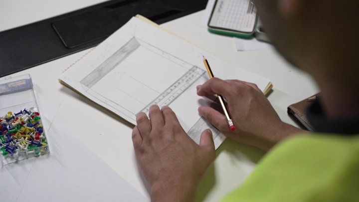 رجل يرسم باستخدام المسطرة والقلم على مكتب، لقطة قريبة.