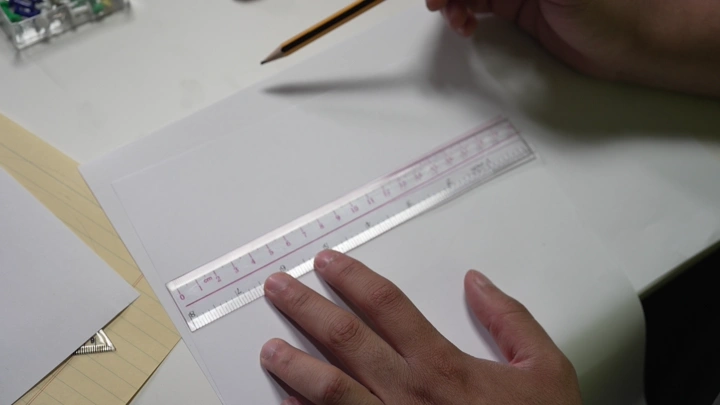 رجل يستخدم المسطرة والقلم على مكتب، لقطة قريبة.