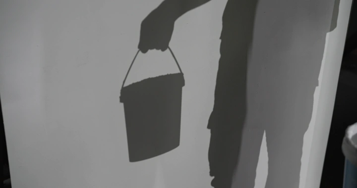 ظل رجل يحمل دلو طلاء على الحائط، لقطة ظلية.