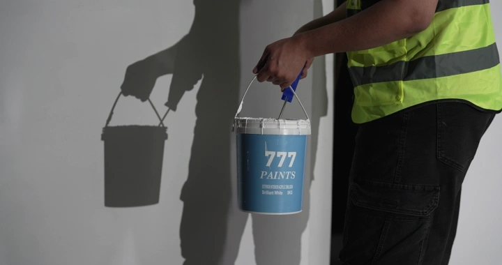 رجل يحمل دلو طلاء بجانب جدار، لقطة جانبية.