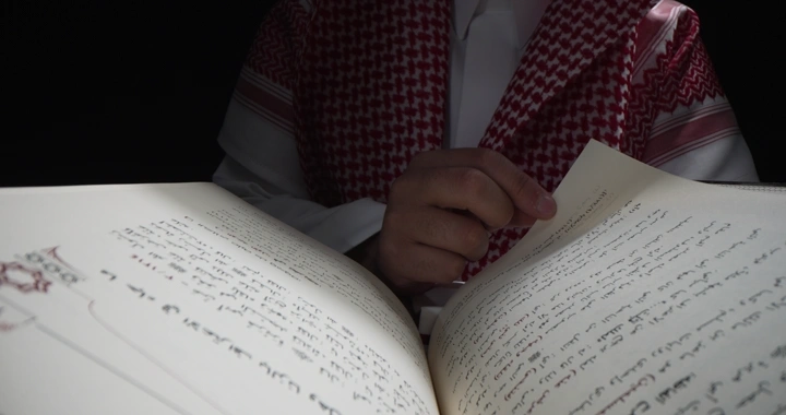 رجل يرتدي ثوبًا يقرأ كتابًا في إضاءة خافتة، لقطة قريبة.