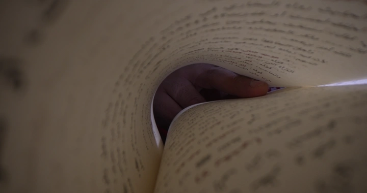 صفحات كتاب مع يد تقلبها، لقطة قريبة.