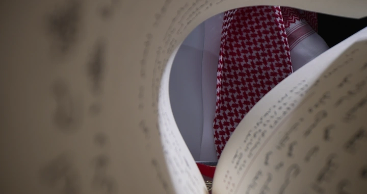 رجل يرتدي شماغ يقرأ كتابًا، لقطة مقربة.