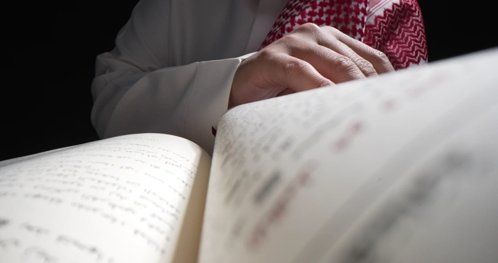 رجل يقرأ كتابًا في ضوء خافت، لقطة مقربة.