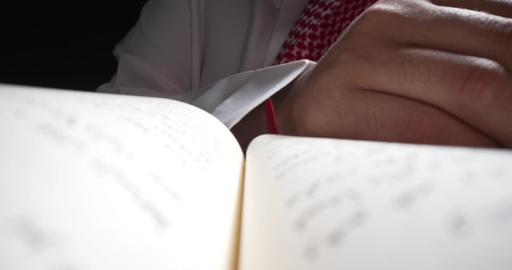 رجل يقرأ كتابًا في إضاءة خافتة، لقطة قريبة.