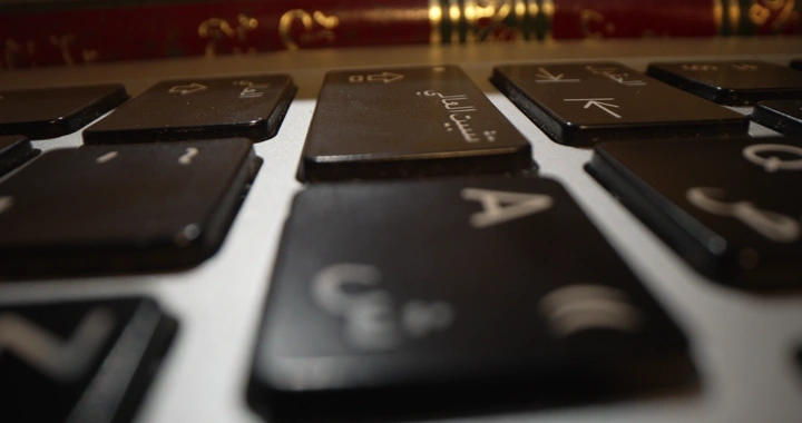 لوحة مفاتيح بين كتب مع شخص يكتب على للوحة مفاتيح، لقطة قريبة.