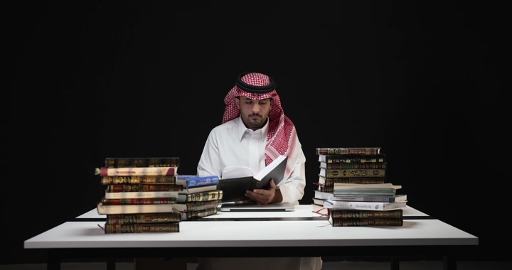 رجل يقرأ بين كتب على طاولة، لقطة امامية.