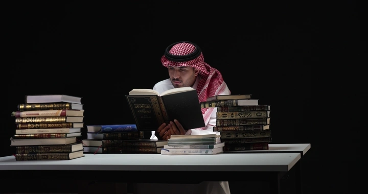 رجل يقرأ بين كتب على طاولة، لقطة امامية