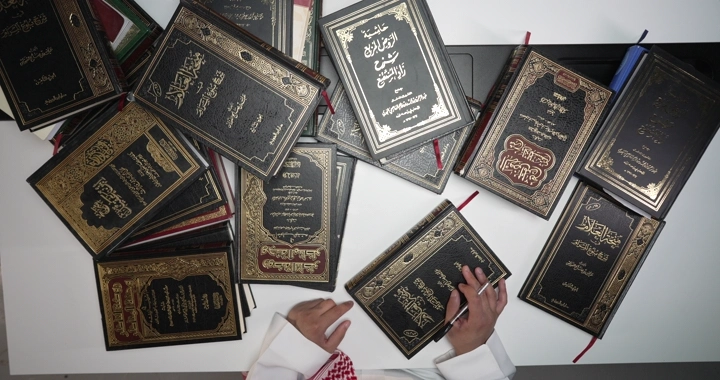 رجل يقرأ بين كتب دينية على طاولة، لقطة من الأعلى.