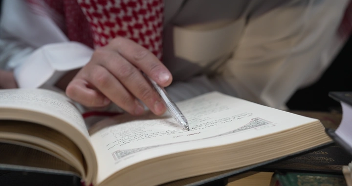 رجل يقرأ كتابًا في الداخل، لقطة مقربة.