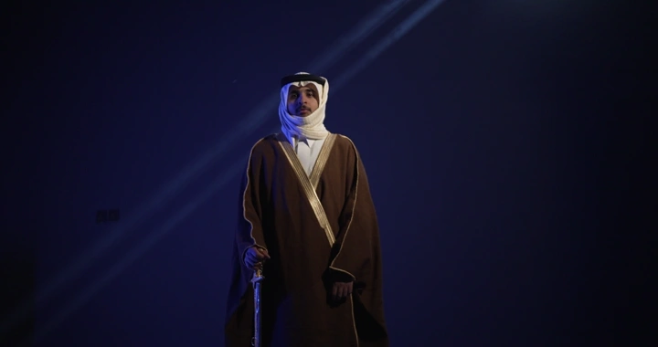 رجل يرتدي الزي التقليدي واقفًا حاملاً سيفًا، إضاءة درامية.