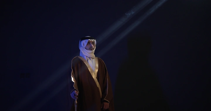 رجل يرتدي ثوباً تقليدياً حاملاً سيفاً، إضاءة درامية.