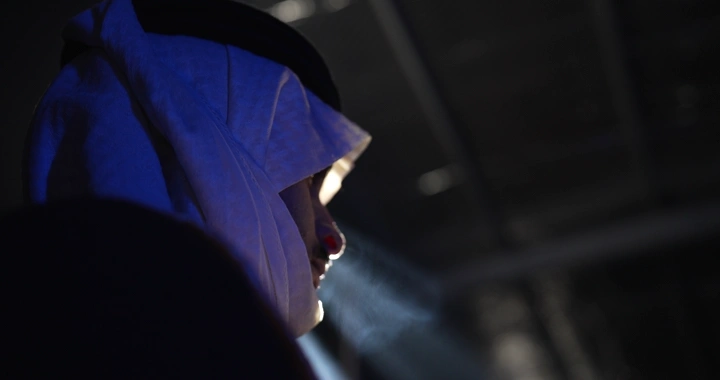 رجل يرتدي غترة في إضاءة خافتة، لقطة جانبية.