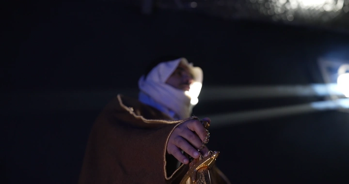 رجل يرتدي بشت ويمسك سيفًا في إضاءة خافتة، لقطة منخفضة.