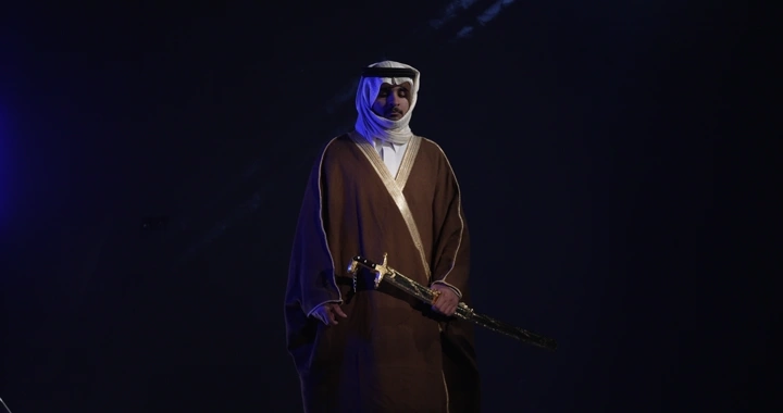 رجل يرتدي ثوباً تقليدياً ويحمل سيفاً. لقطة واسعة.