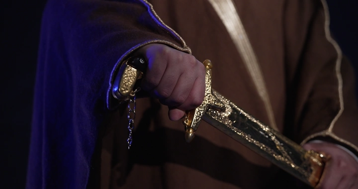 رجل يحمل سيفًا ذهبيًا مزخرفًا، لقطة قريبة.