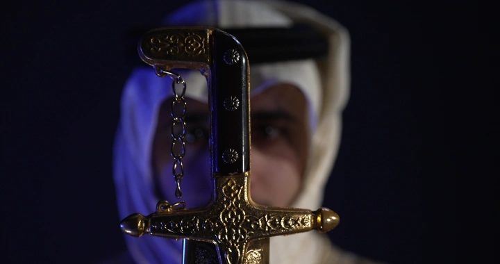 رجل يرتدي زي تقليدي يحمل سيفًا مزخرفًا، لقطة مقربة.