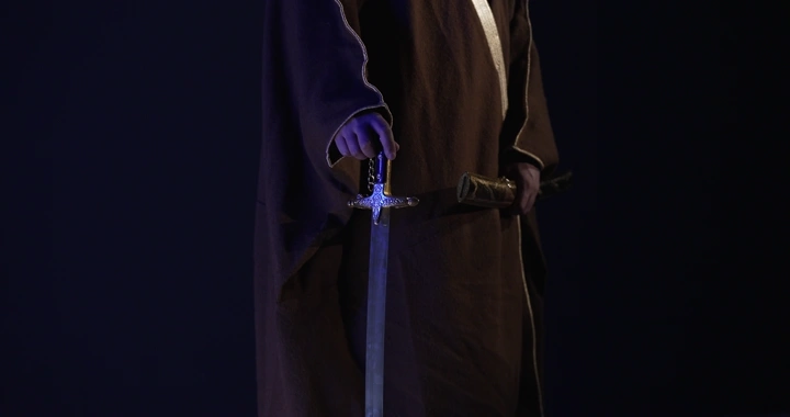 رجل يحمل سيفًا في إضاءة خافتة، لقطة قريبة.