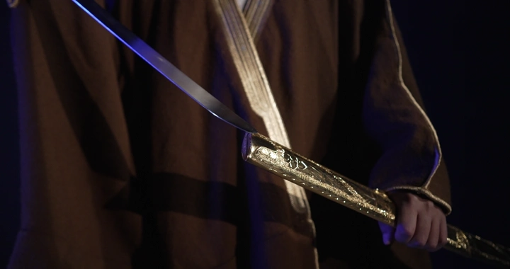 رجل يرتدي بشت بنية يحمل سيفًا مزخرفًا، لقطة مقربة.