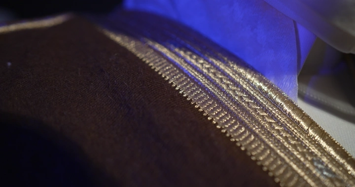 تفاصيل بشت بني مزخرف بخيوط ذهبية، لقطة مقربة.