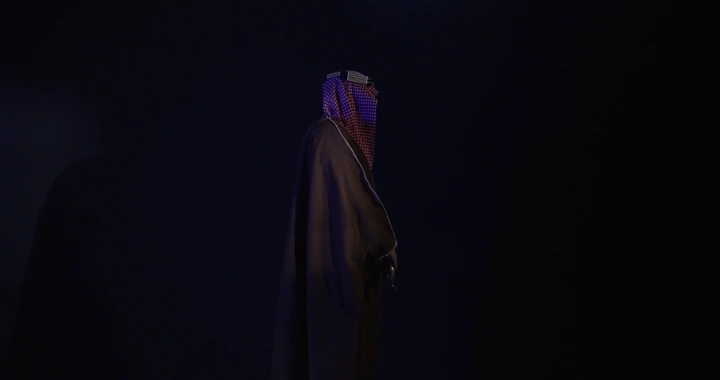 رجل يرتدي الزي التقليدي ويمسك سيفًا، خلفية سوداء، لقطة جانبية.