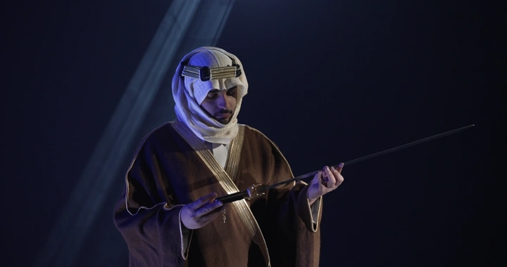 رجل يرتدي الزي التقليدي يمسك سيفًا في إضاءة سينمائيه.