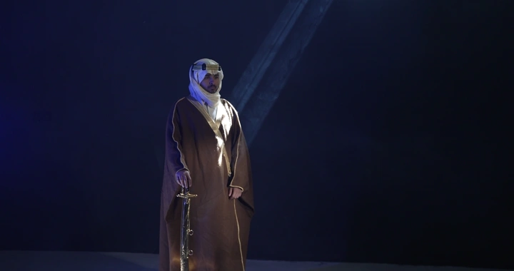 رجل يرتدي عقالًا ويمسك سيفًا في إضاءة سينمائيه..