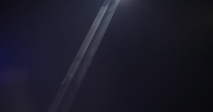 رجل يمشي تحت شعاع ضوء في الظلام، لقطة ليلية.