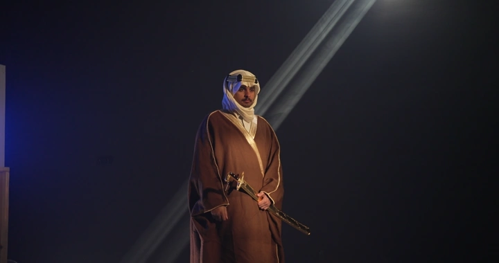 رجل يرتدي ثوبًا تقليديًا ويمسك سيفًا في إضاءة سينمائيه..