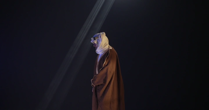 رجل يرتدي بشت تقليدية تحت ضوء كشاف، لقطة جانبية.