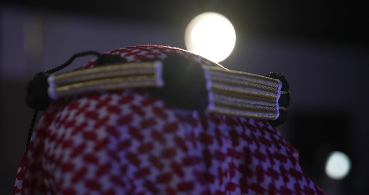 عقال مقصب على شماغ أحمر في إضاءة ليلية، لقطة مقربة.