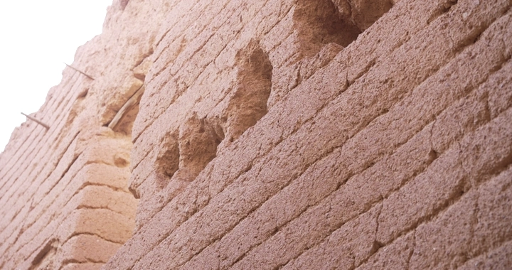 Old mud brick wall in daylight, close-up shot.