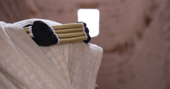 Man wearing traditional headwear inside mud house, close-up shot.