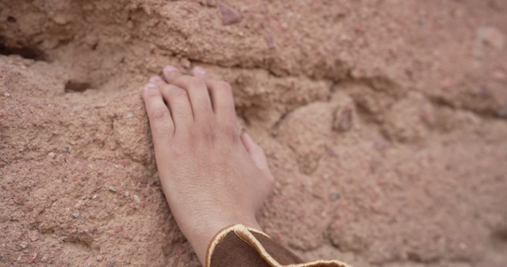 يد تلمس جدار طيني، لقطة قريبة.