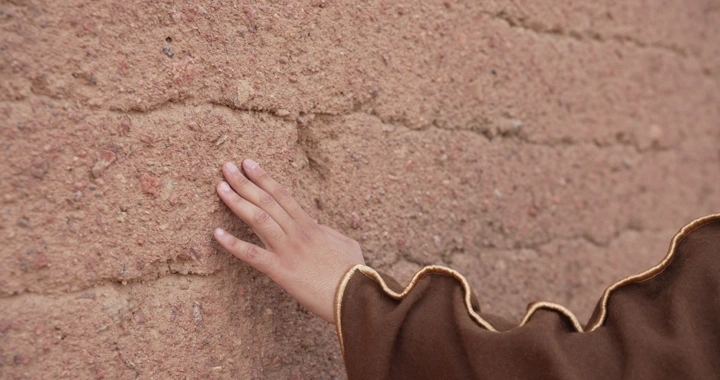 Hand touching mud wall, close-up shot.