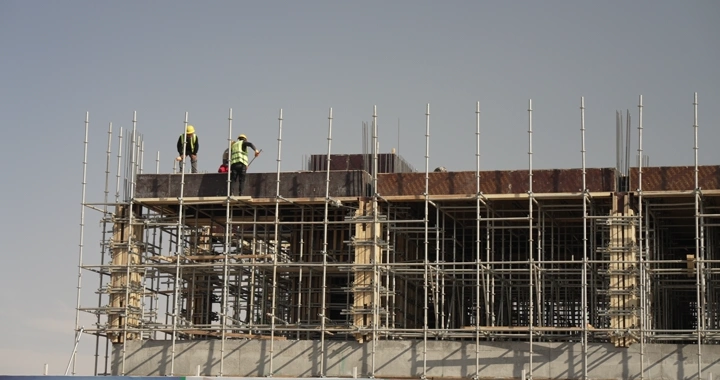 Construction workers at a construction site, shot from a low angle.
