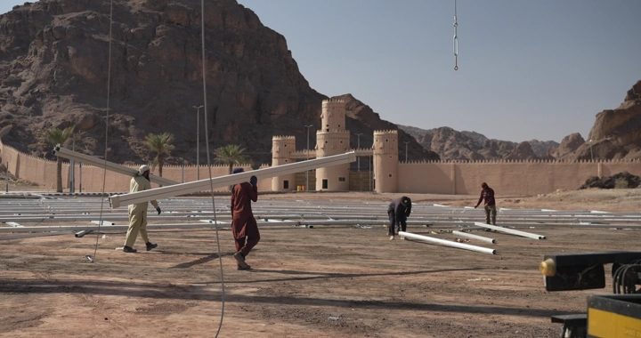 Workers at a construction site in front of an ancient fort, daytime shot.