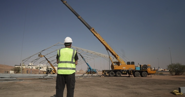 Engineer wearing helmet and vest at construction site during daytime, rear view shot.