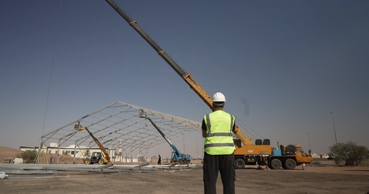 Engineer in vest and helmet at construction site during daytime, rear view shot.