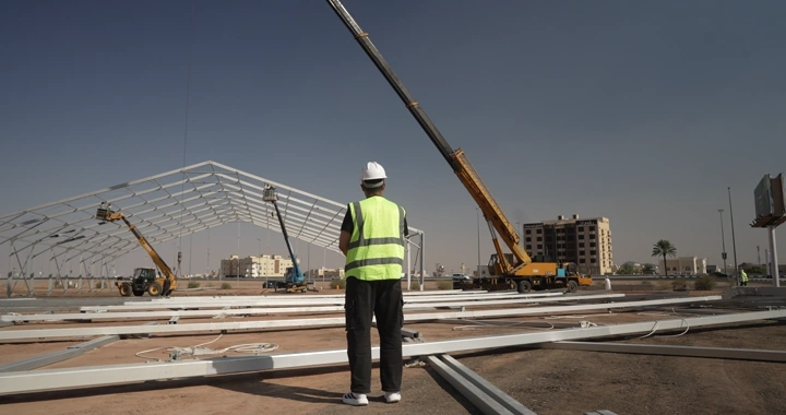 Engineer in vest and helmet at construction site, rear view shot.