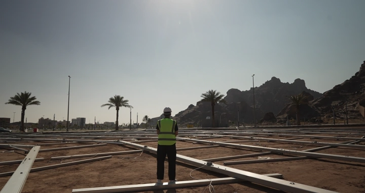 Engineer standing at a construction site with mountains in the background, daytime shot.