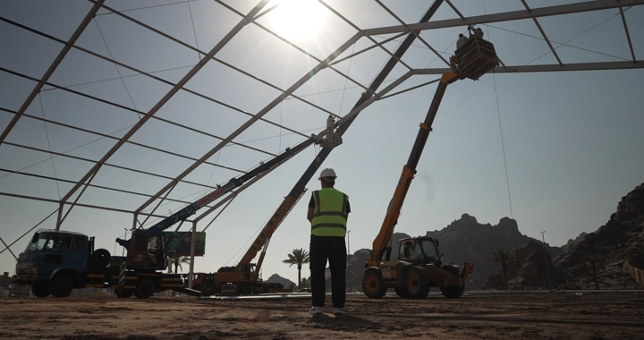 Engineer standing at construction site with cranes, back view.