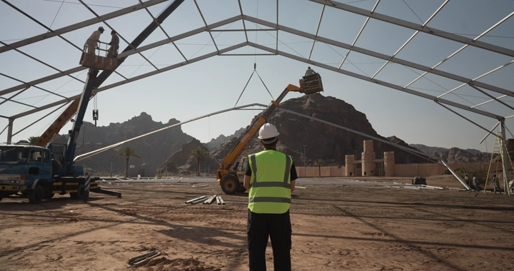 Engineer wearing helmet and safety vest at desert construction site, daytime shot.