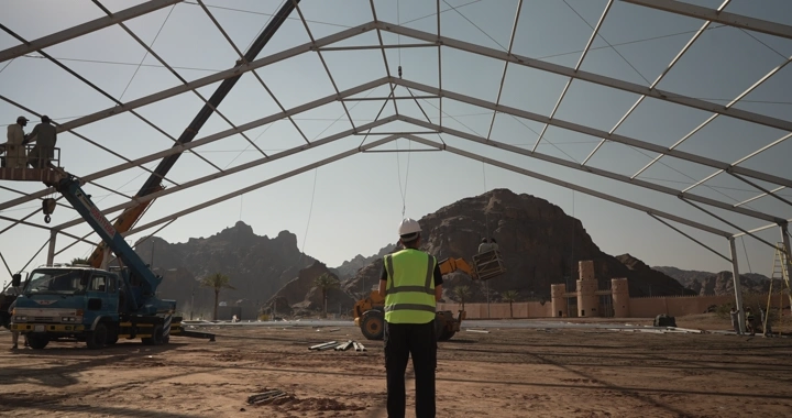 An engineer wearing a reflective vest stands at a construction site, daytime shot.