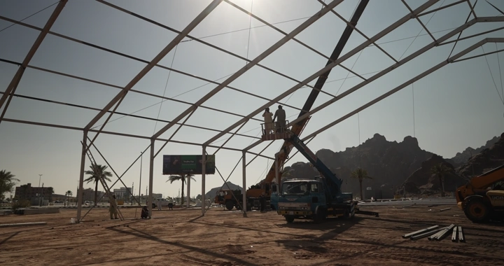 A construction site with workers on a crane, daytime shot.