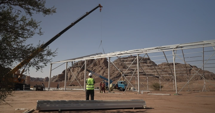 Engineer in vest and helmet standing at desert construction site, daytime shot.