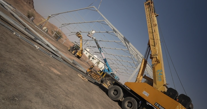 مهندس يرتدي سترة أمان يقف في موقع بناء صحراوي، لقطة نهارية.