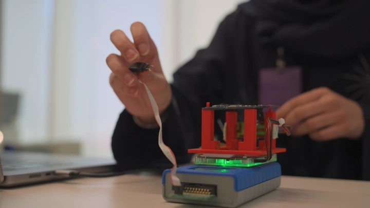 موظف يعمل على جهاز إلكتروني في مكتب، لقطة مقربة.